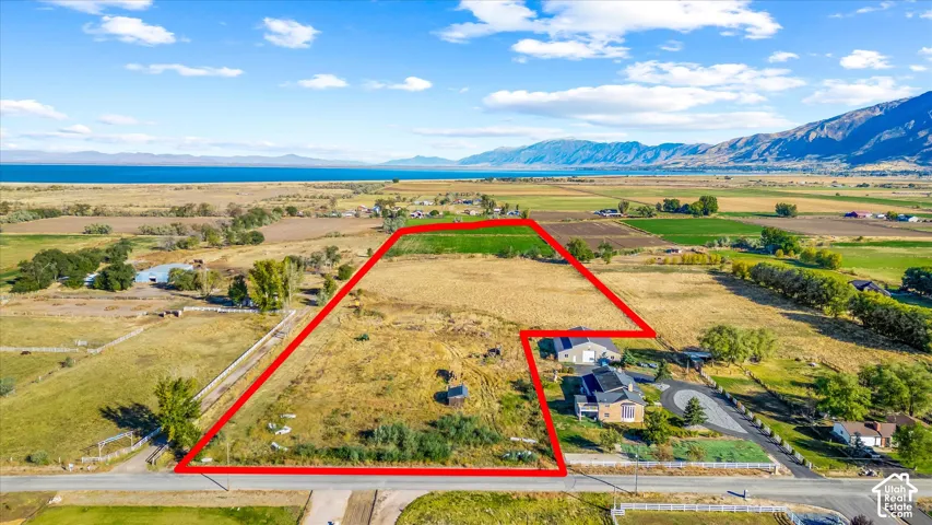 Expansive land parcel with surrounding agricultural fields, distant body of water, and mountainous terrain
