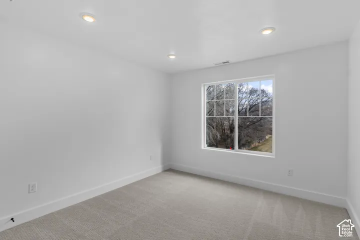 Recessed lighting, light-toned carpeting, white walls, white trim, and a window with a white frame