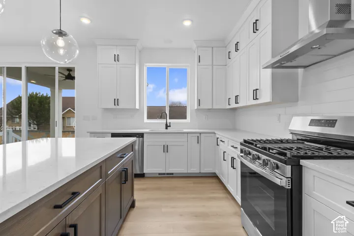 White shaker cabinetry, stainless steel appliances, wood-finish flooring, central island with countertop, and sliding glass door to exterior