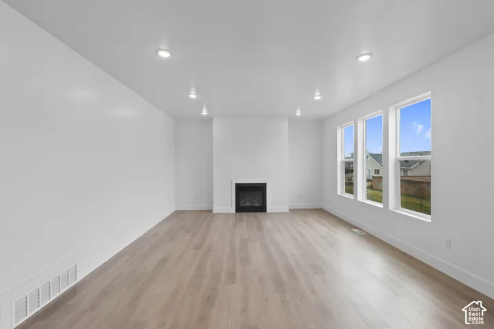Recessed lighting, light wood-finish flooring, three vertical windows, and a built-in fireplace