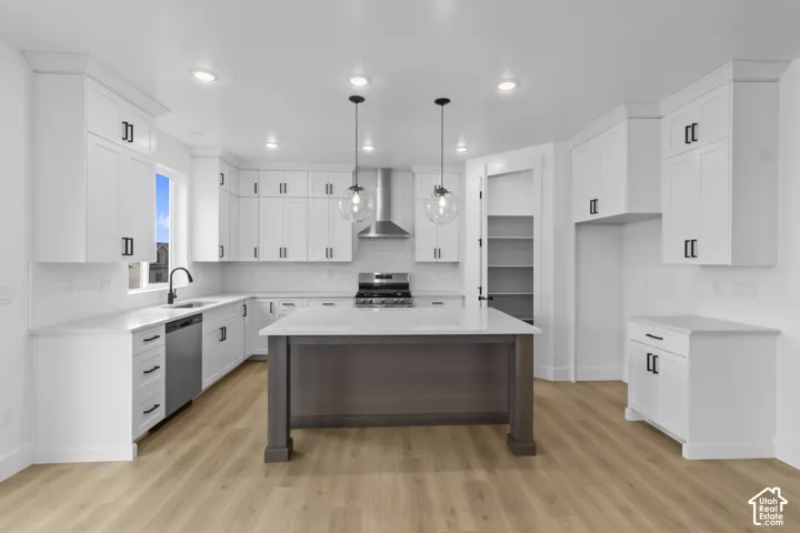 White shaker cabinetry with matte black hardware, integrated stainless steel appliances, central island with seating, recessed lighting, and wood-finish flooring