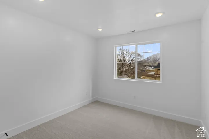 Recessed ceiling lighting, white painted walls, window with muntins, light-toned carpet flooring, mountain scenery