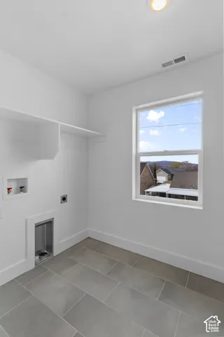 White walls, tiled flooring, built-in shelving, recessed ceiling light, and a window