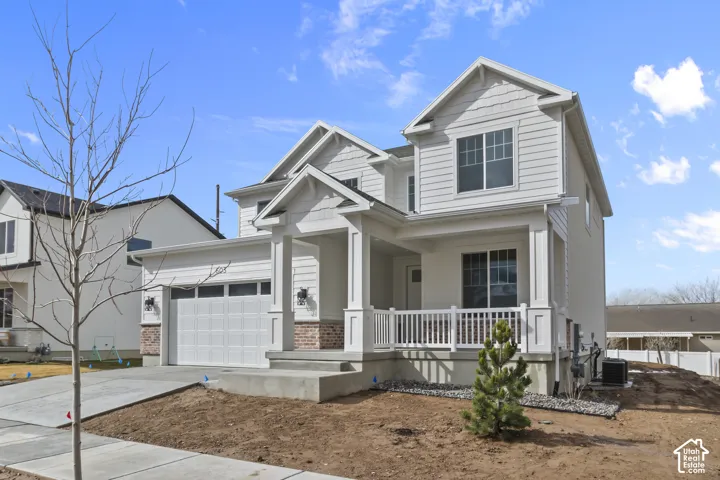 Contemporary exterior with white siding, brick accents, a covered front porch, and an attached two-car garage
