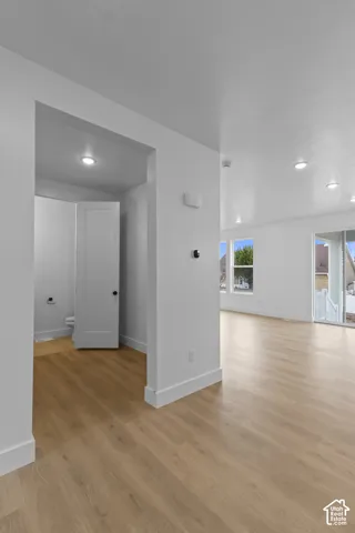 Open-concept layout with wood-finish flooring, recessed lighting, and white walls