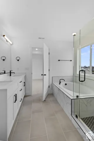 Expansive tiled flooring complementing a dual vanity with undermount sinks and matte black fixtures