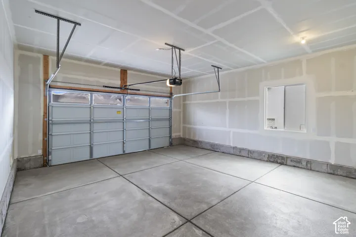 Spacious garage featuring a concrete floor, overhead lighting, an automatic garage door opener, and an integrated window