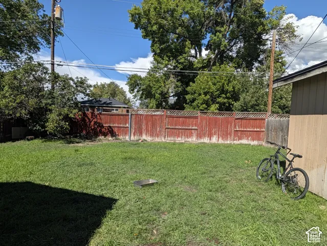 Expansive grassy yard with wood fencing and mature trees