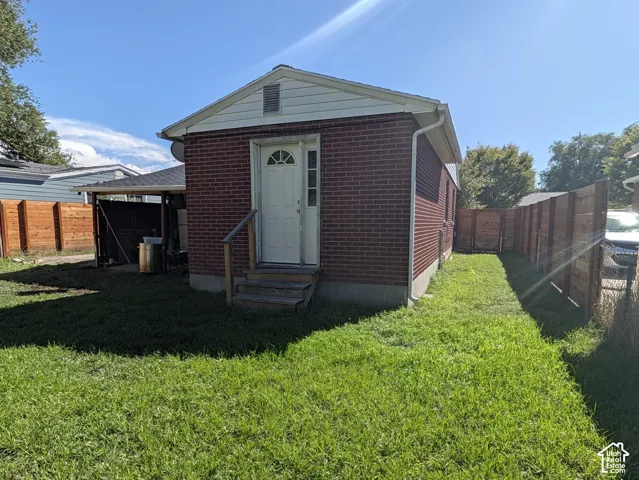 Brick exterior with a white entry door, wood steps, and a side-yard privacy fence