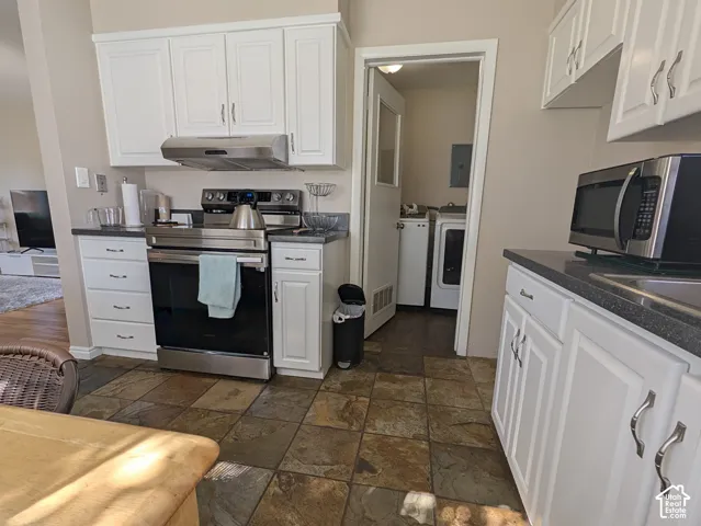 White cabinetry with brushed nickel hardware, stainless steel appliances, dark stone countertops, and multi-toned tile flooring