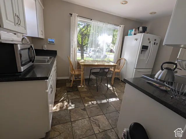 Kitchen featuring recessed lighting, white cabinetry, dark countertops, a double basin stainless steel sink, and tile flooring