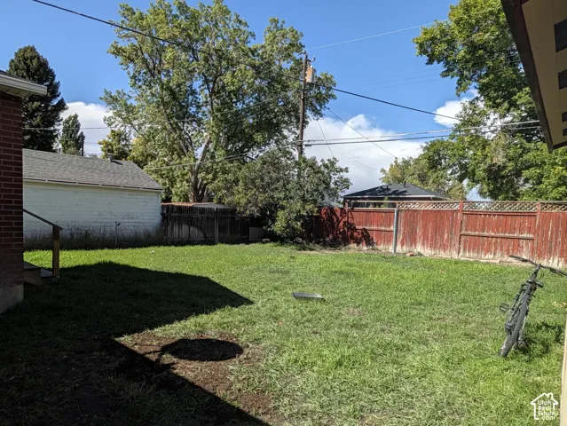 Expansive green lawn with a wooden privacy fence and mature trees
