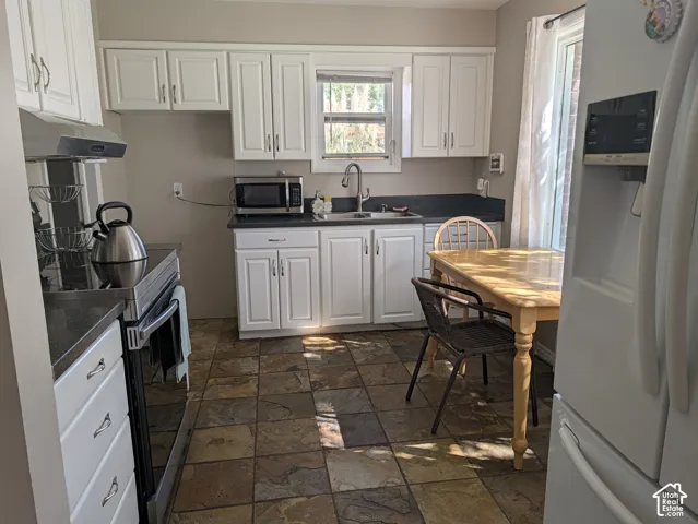 Kitchen featuring white cabinetry, dark countertops, a stainless steel range, and tile flooring
