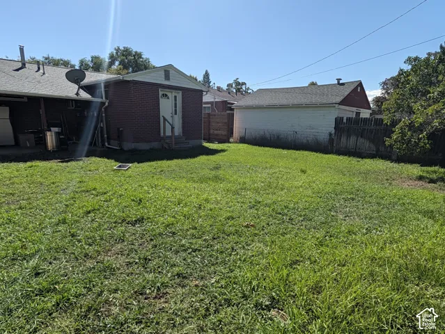 Expansive grassy yard with brick exterior, white trim, and a detached structure