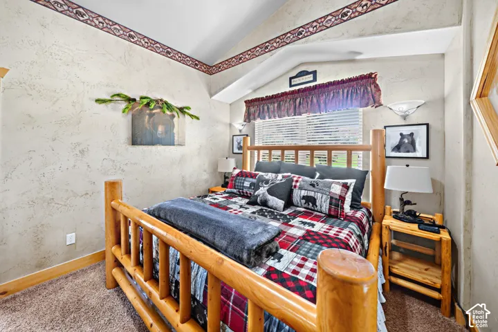 Vaulted ceiling with decorative trim, textured wall finishes, and wood-frame bed