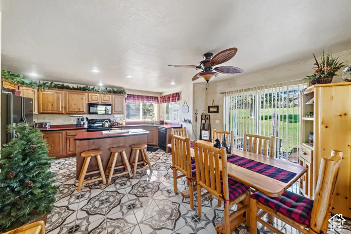Kitchen featuring wood cabinetry, a center island with seating, patterned tile flooring, and a dining area with direct outdoor access