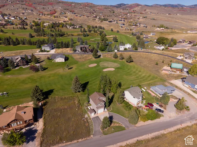 Expansive property featuring a golf course, residential structures, and mountainous terrain
