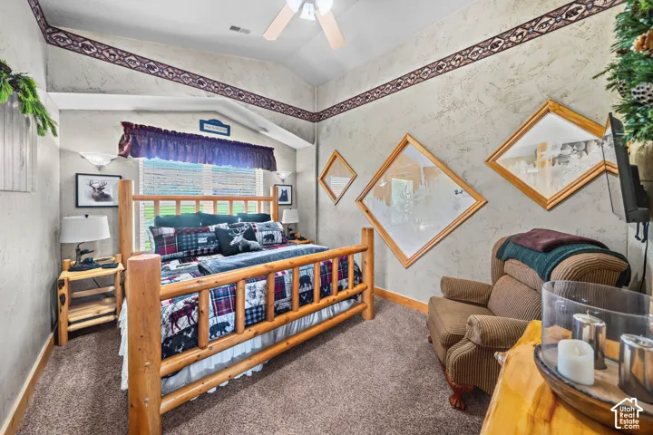 Carpeted bedroom with a sloped ceiling and ceiling fan