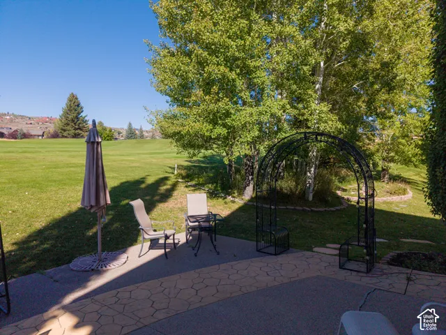 Paver patio with a stone inlay border, mature trees, and a decorative metal archway