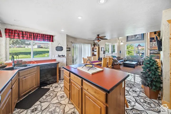 Kitchen featuring wood cabinetry, a center island with a solid surface countertop, black appliances, and patterned floor tiles