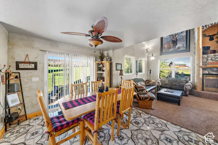 Open-concept living area with a stone fireplace, high vaulted ceiling, and mixed flooring