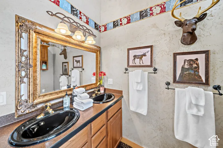 Dual black oval sinks set into a vanity with a dark countertop and wood-finish cabinetry