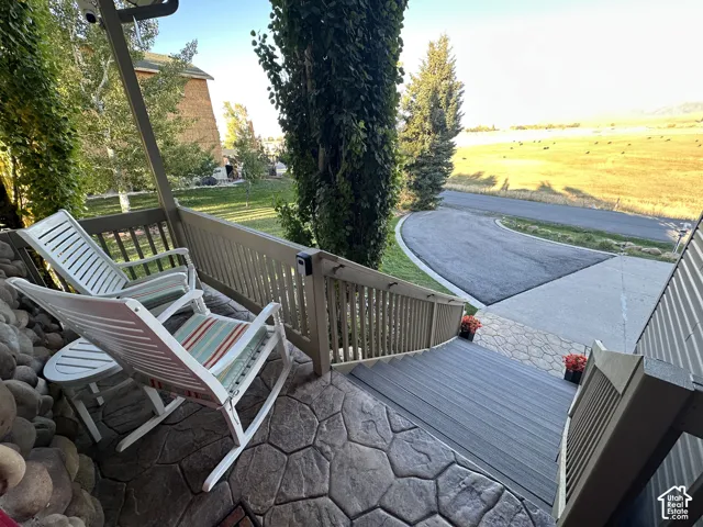 Stamped concrete patio, composite decking stairs, wood railing, paved driveway, mature landscaping