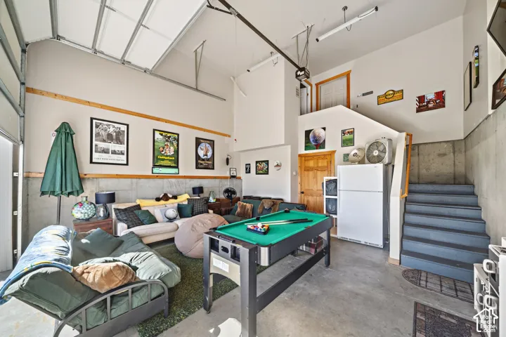 High-ceiling garage space with exposed structural elements, concrete flooring, and a built-in staircase
