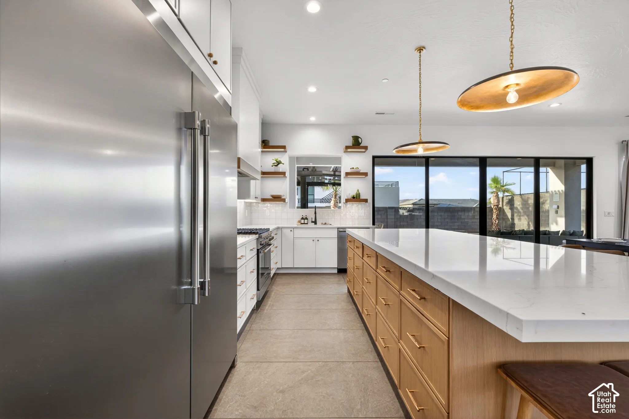 Gourmet kitchen with stainless steel appliances, large center island with light-toned cabinetry, white countertops, and sliding glass doors