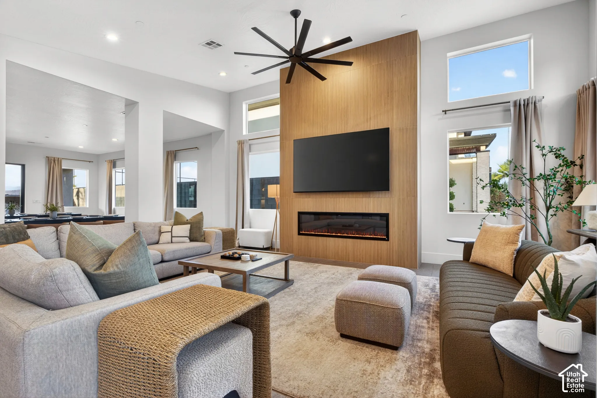 Spacious living area featuring high ceilings, a contemporary ceiling fan, and an integrated linear fireplace