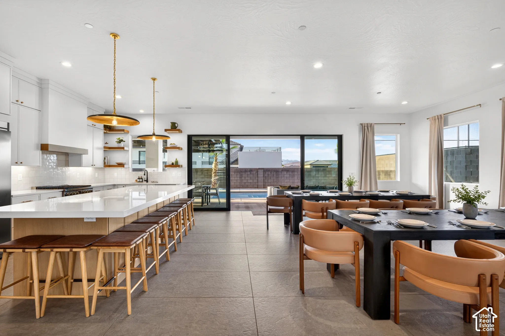 Spacious open-concept living area with a large kitchen island, sleek white cabinetry, a tiled backsplash, and recessed lighting