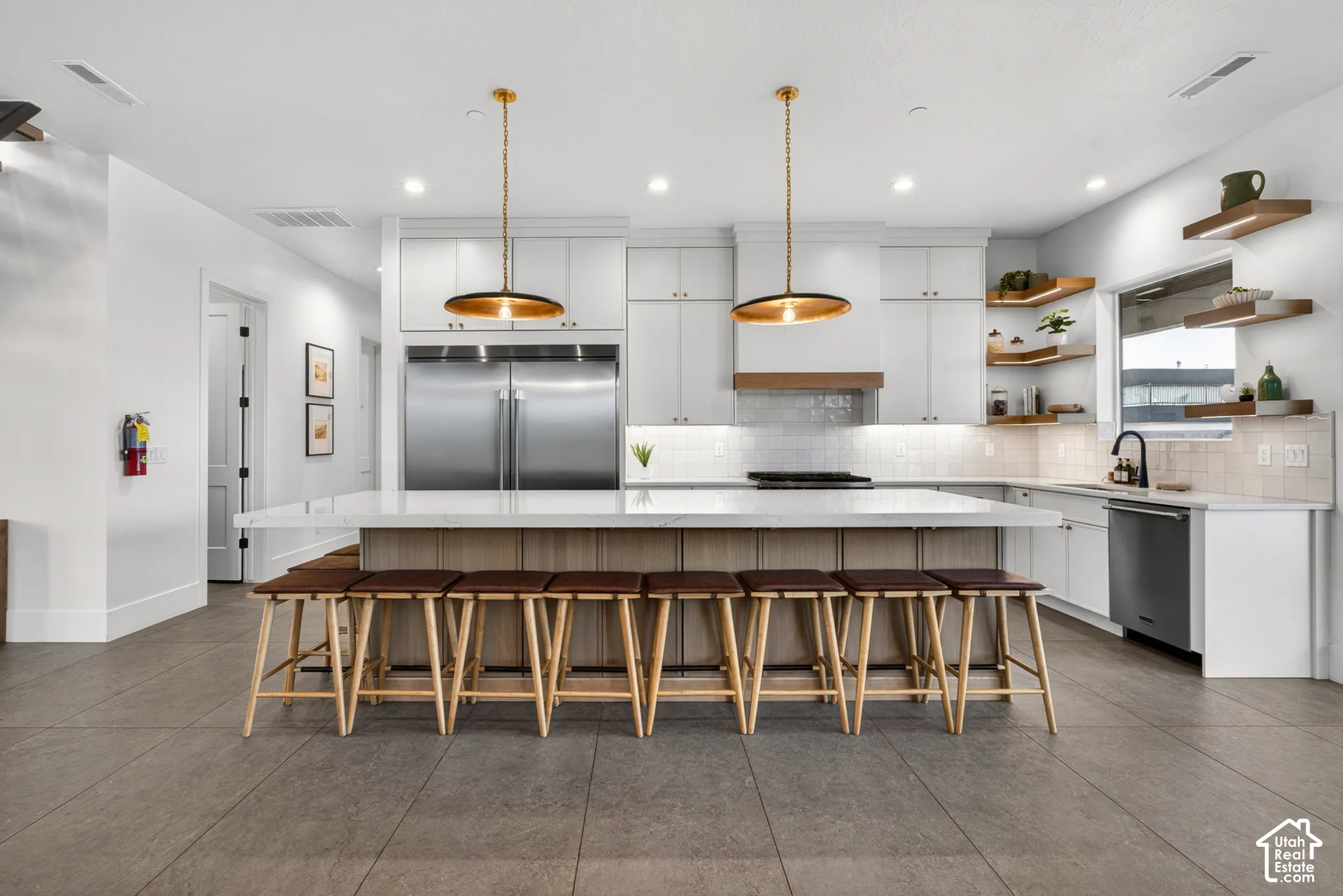 Kitchen featuring a large center island with seating, white cabinetry, stainless steel appliances, and integrated ceiling and pendant lighting