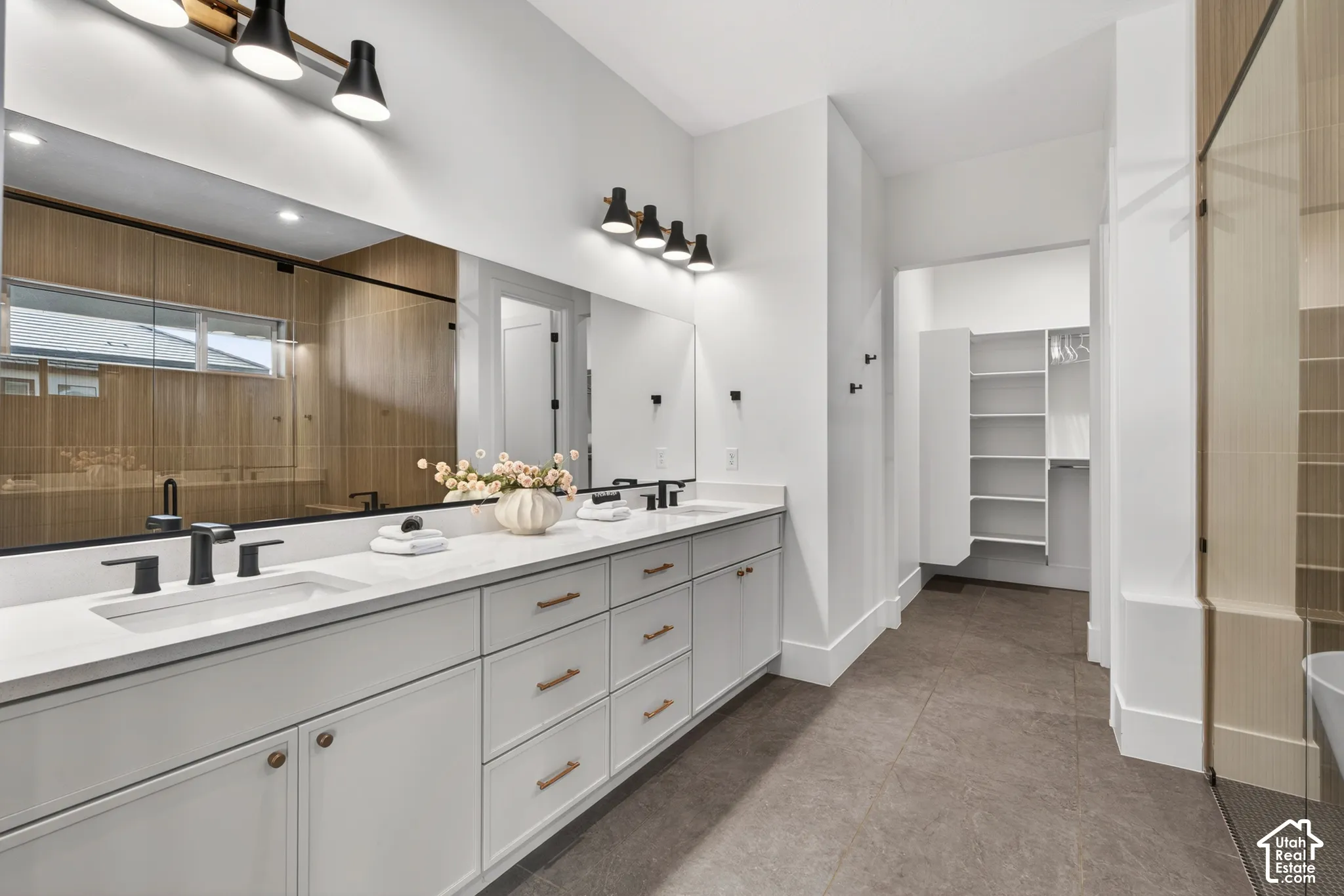 Dual vanity with white cabinetry, matte black fixtures, and a large integrated mirror