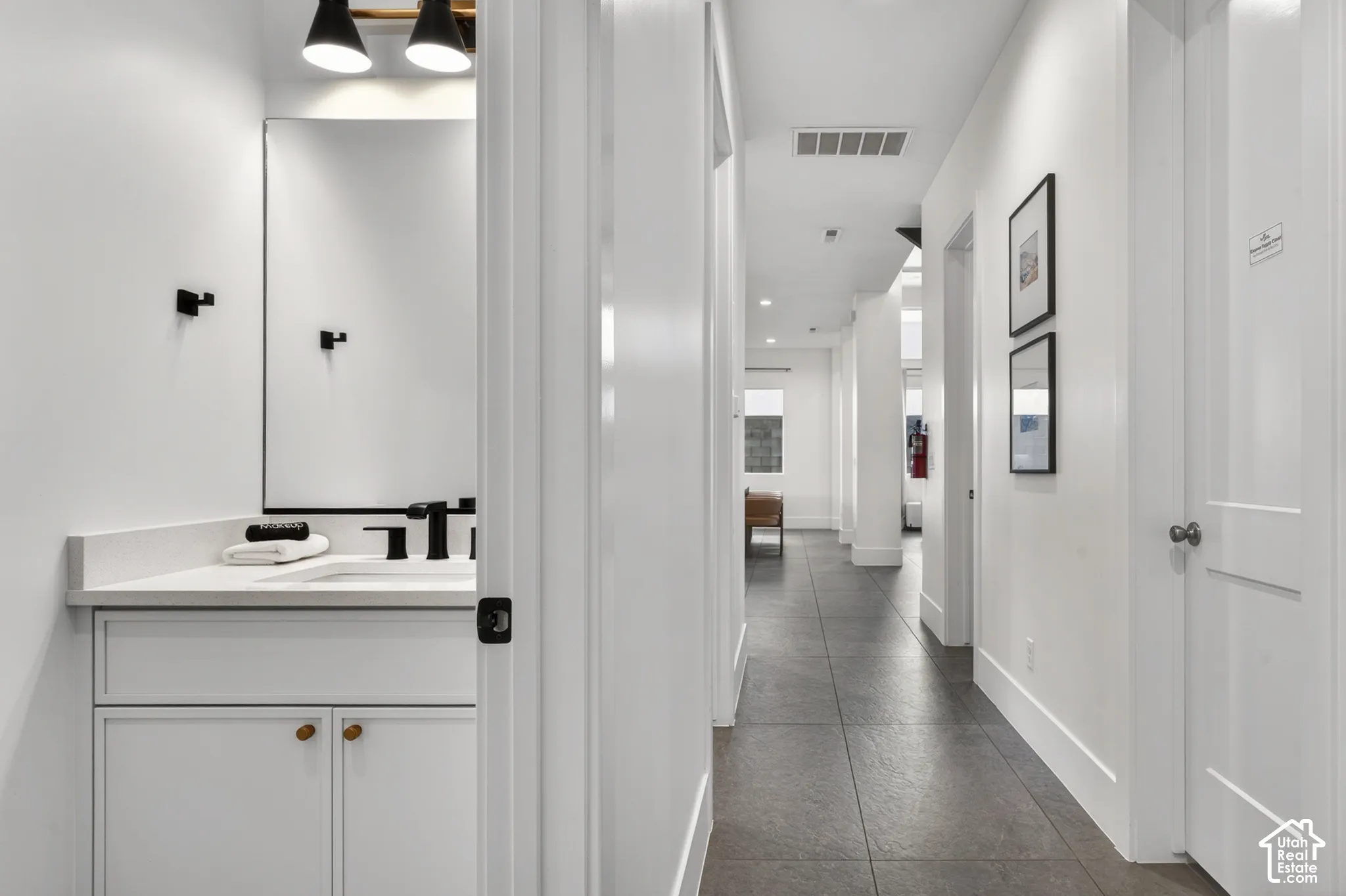 White vanity with a rectangular basin, quartz countertop, and matte black faucet