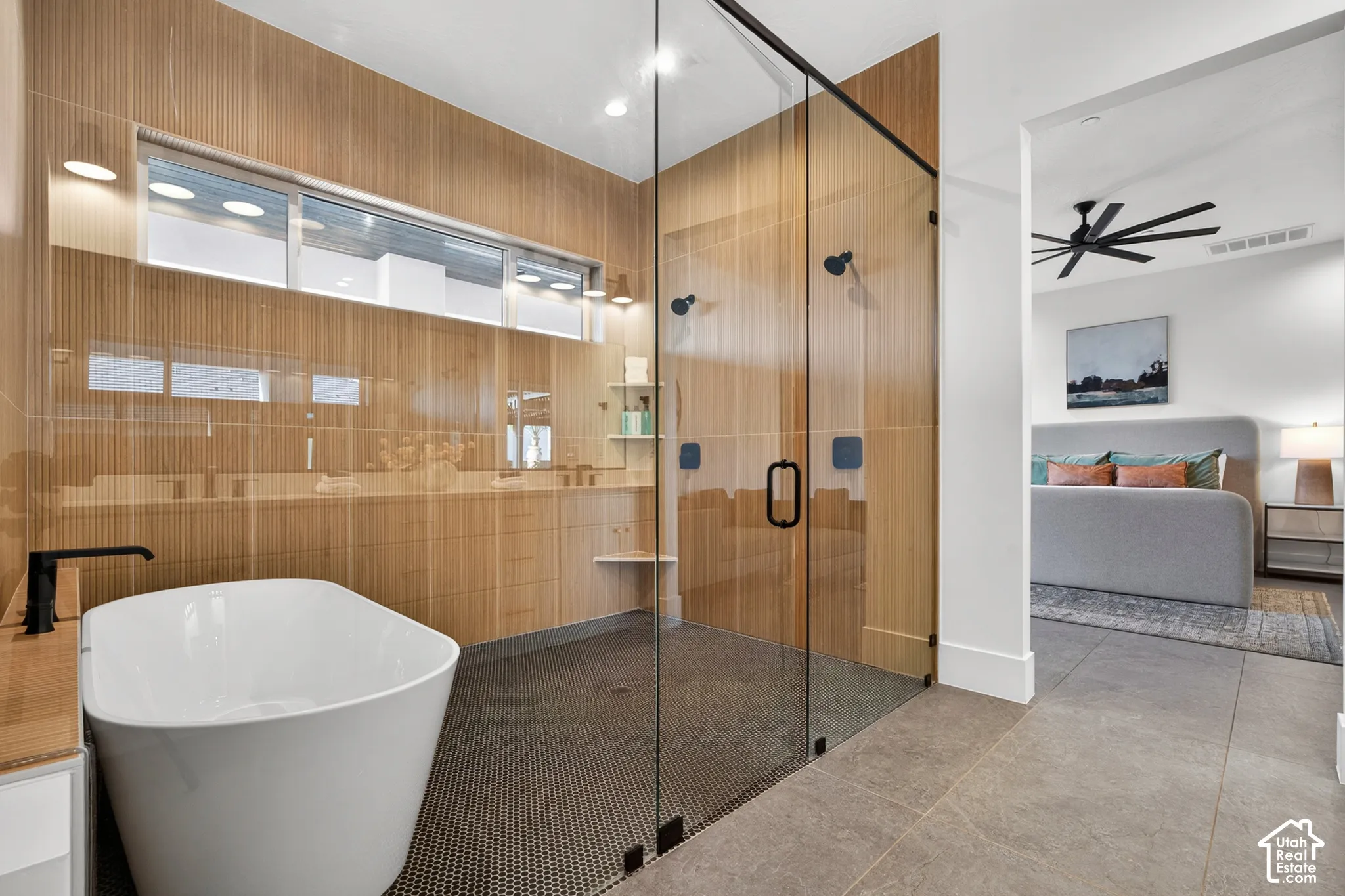 Freestanding bathtub, expansive glass-enclosed shower with black fixtures, and wood-finish wall paneling