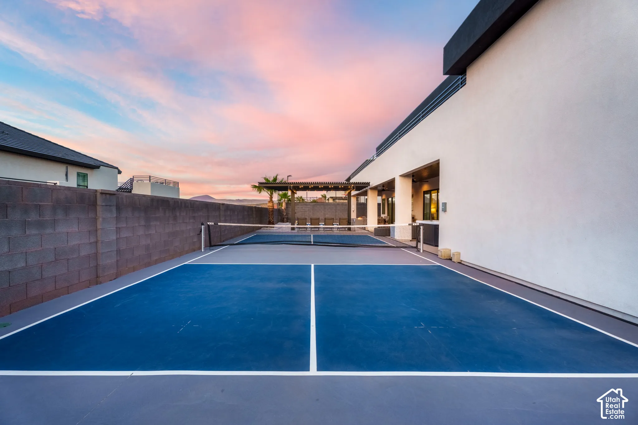 Private outdoor pickleball court, smooth hardscaping, stucco exterior, and a shaded pergola