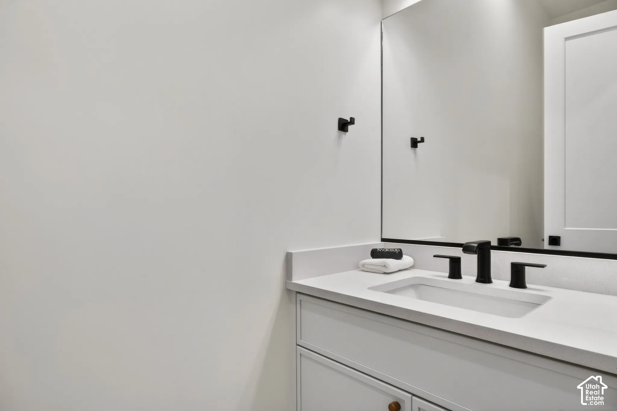 Built-in vanity with a white countertop, undermount sink, matte black faucet, and a large wall-mounted mirror