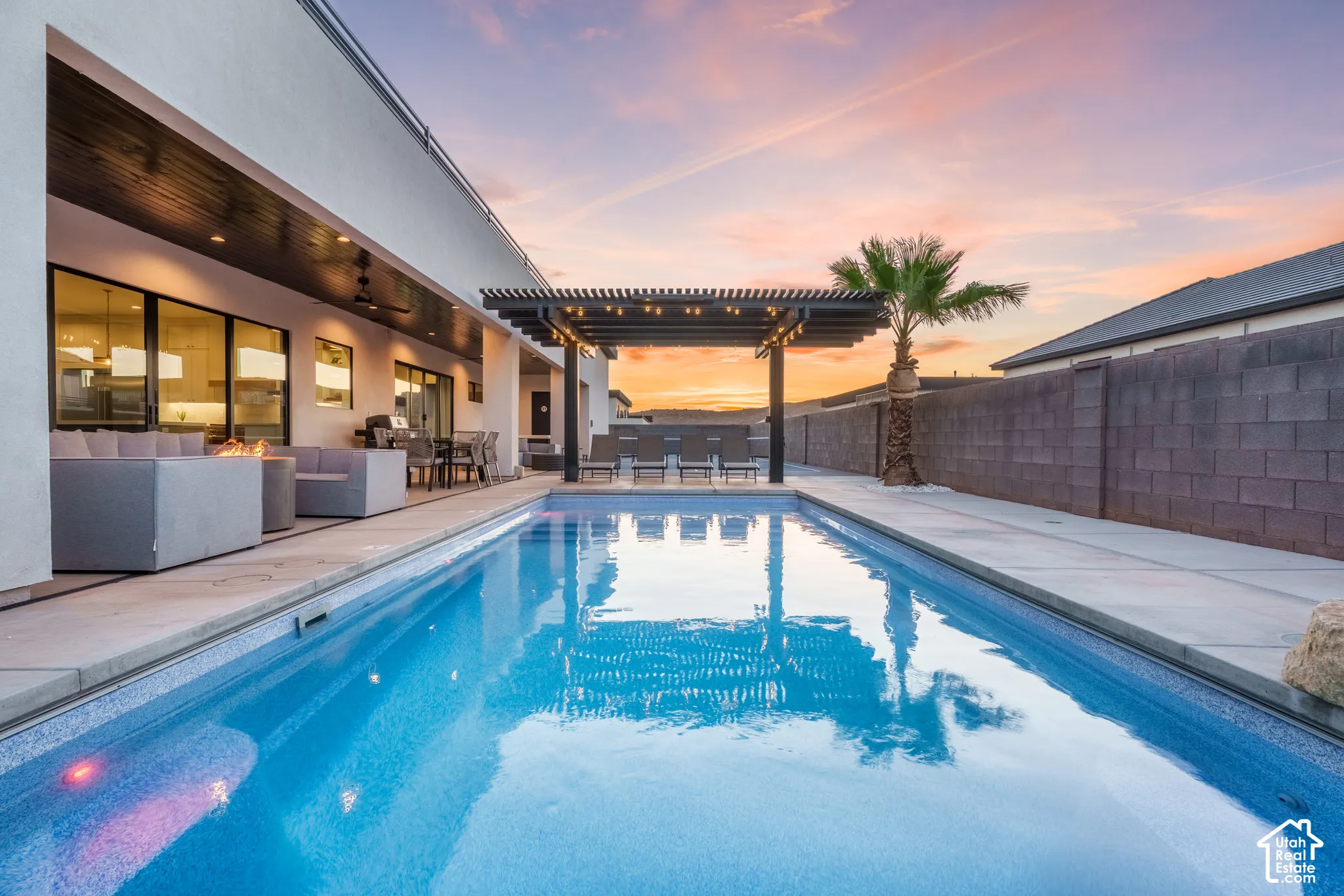 Rectangular swimming pool with surrounding concrete decking, an attached covered patio, and a pergola structure
