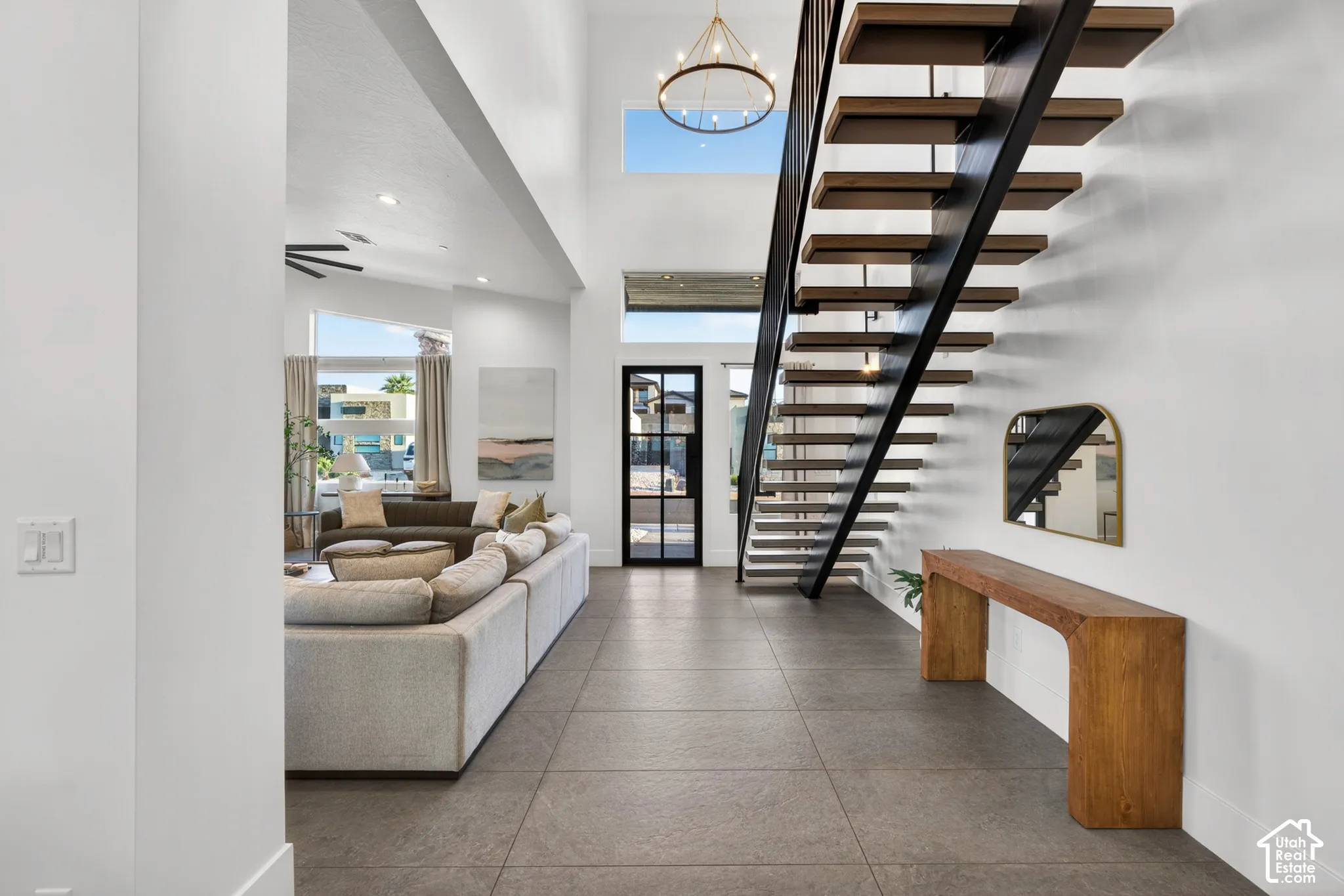 Two-story entry with a floating staircase, open-tread wood stairs, and a decorative chandelier