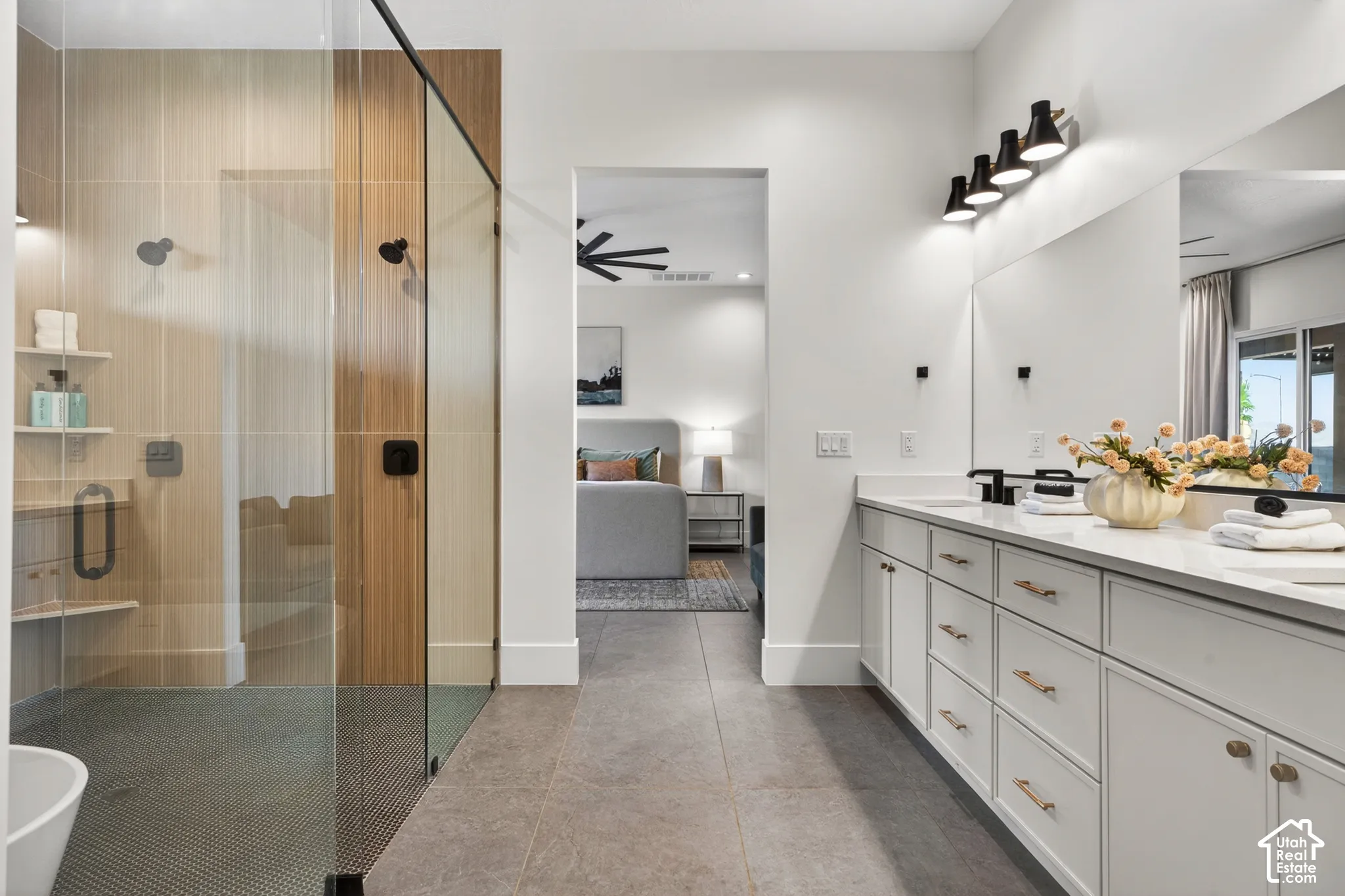 Dual vanity with white cabinetry, matte black fixtures, and a glass-enclosed shower with wood-finish paneling and integrated shelving