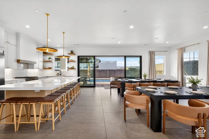 Spacious open-concept living area with a large kitchen island, sleek white cabinetry, a tiled backsplash, and recessed lighting