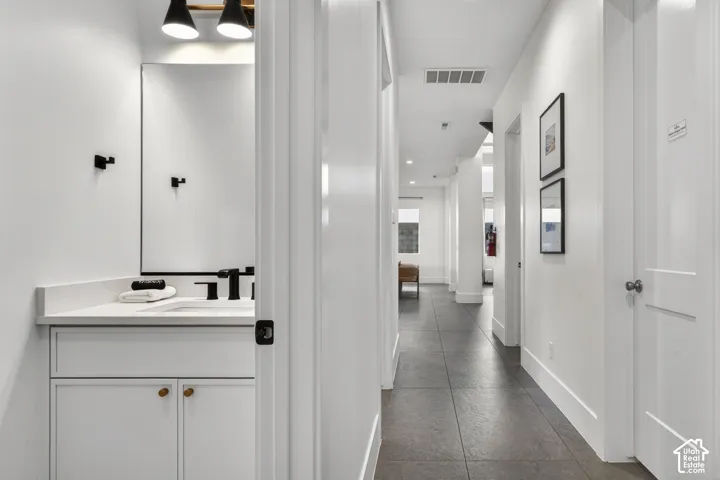 White vanity with a rectangular basin, quartz countertop, and matte black faucet
