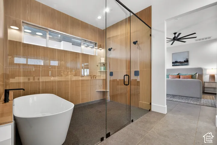 Freestanding bathtub, expansive glass-enclosed shower with black fixtures, and wood-finish wall paneling