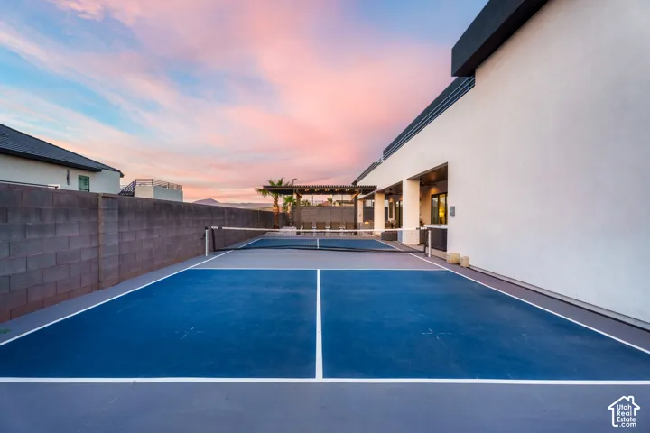 Private outdoor pickleball court, smooth hardscaping, stucco exterior, and a shaded pergola