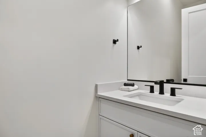 Built-in vanity with a white countertop, undermount sink, matte black faucet, and a large wall-mounted mirror