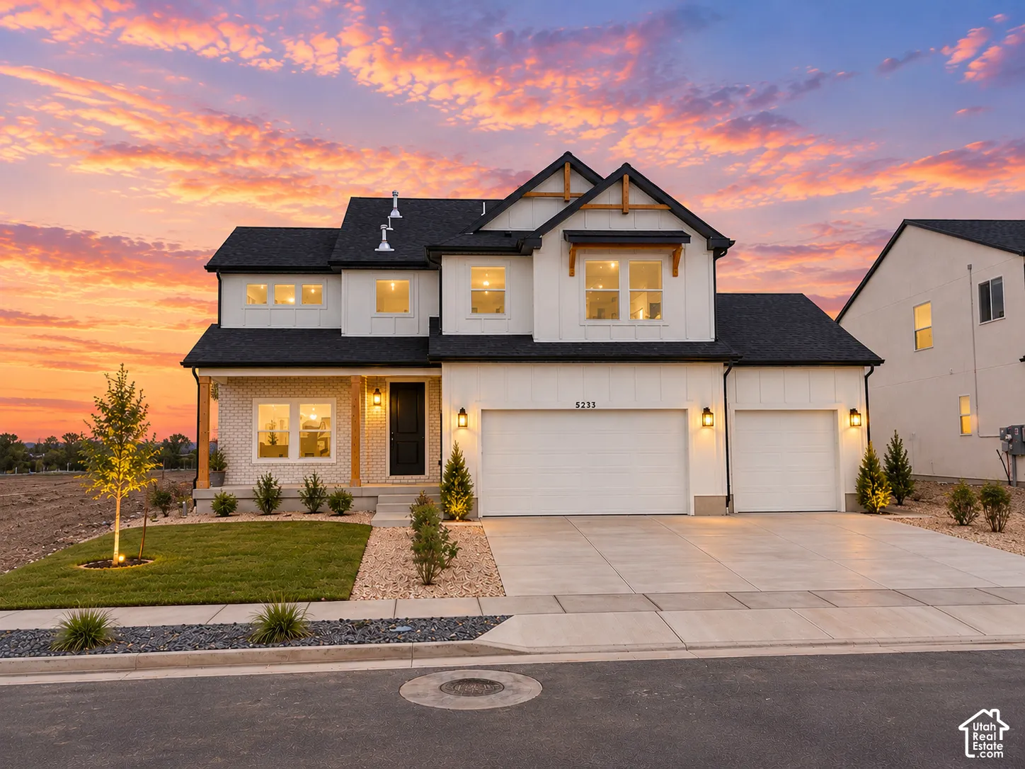 Modern two-story exterior featuring white board-and-batten siding, light-toned brick accents, timber beam detailing, and a three-car garage