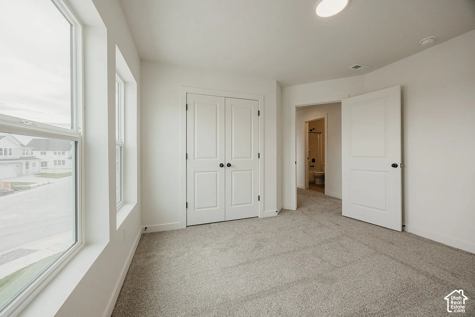 Carpeted room with multiple windows, bi-fold closet doors, and recessed lighting