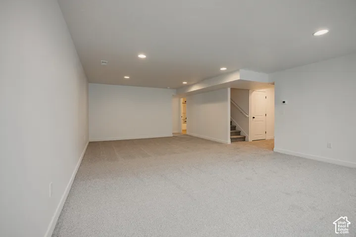 Expansive interior space with light-toned carpet, recessed lighting, and crisp white walls