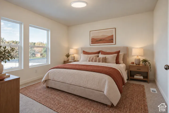 Light-colored walls, recessed ceiling fixture, two large windows, wood-finish nightstands, and light-toned carpeting