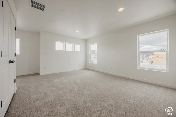 Recessed lighting, light-toned carpeting, white walls, and multiple windows with white frames